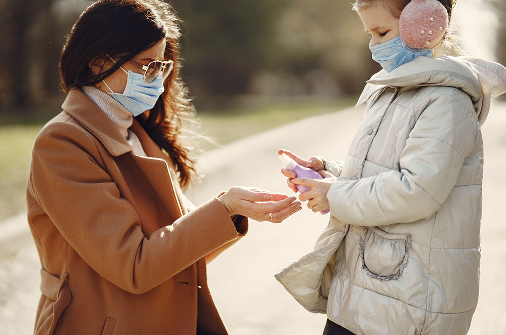 daughter spraying hands of mother with disinfection liquid 4000623